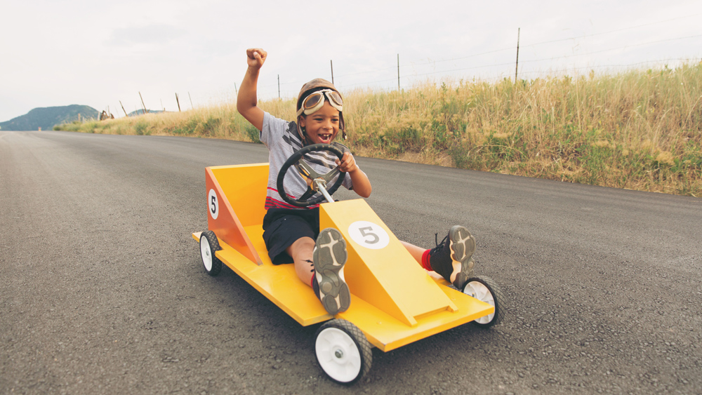 young boy riding in a soap box car