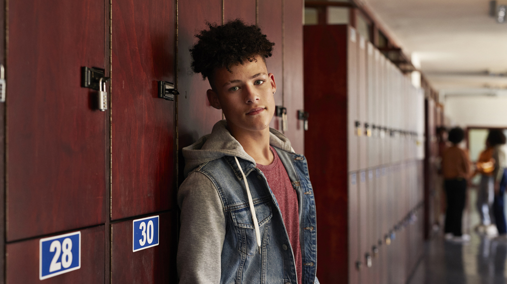 young man standing by lockers in school