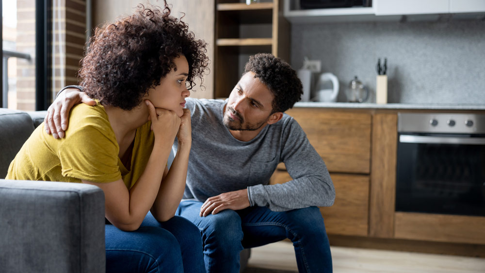 man and woman sitting on couch talking