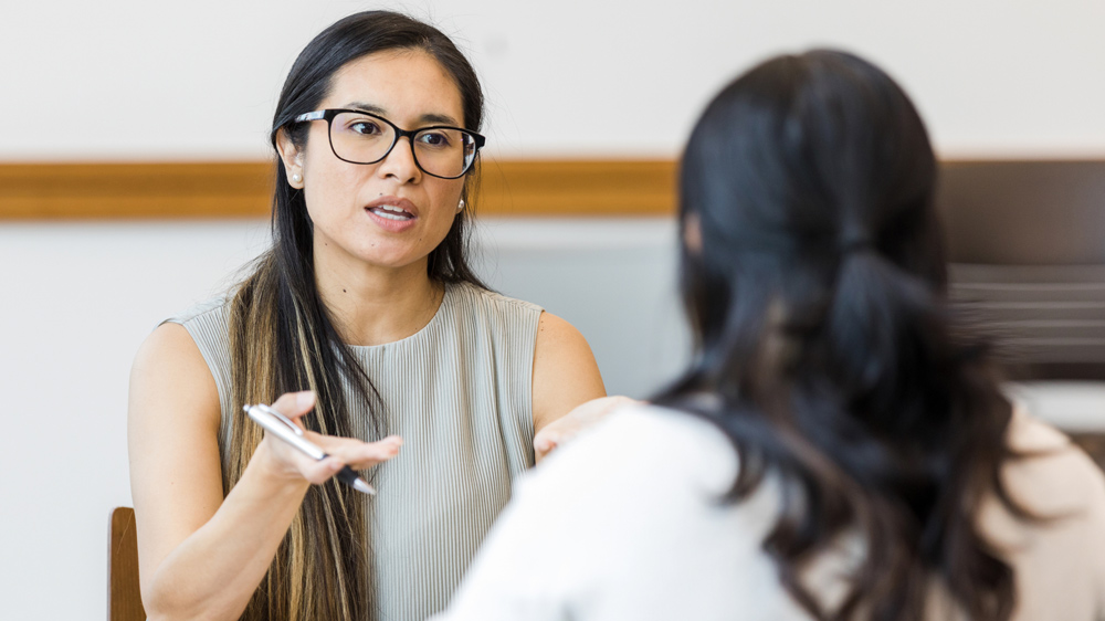 a woman having a serious conversion with another woman in office setting