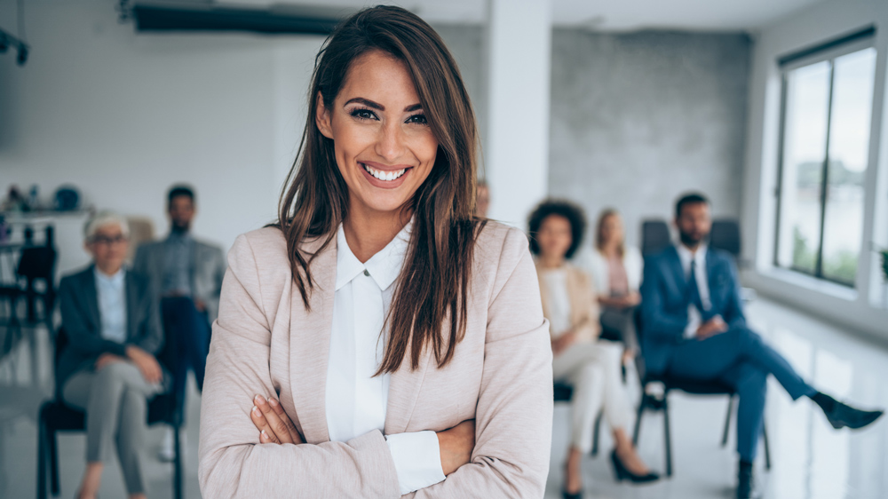 Smiling public speaker in front of her colleagues in conference hall