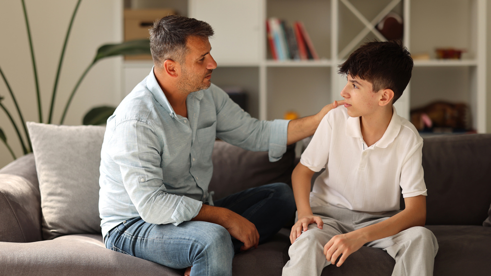 father and son sitting on couch talking