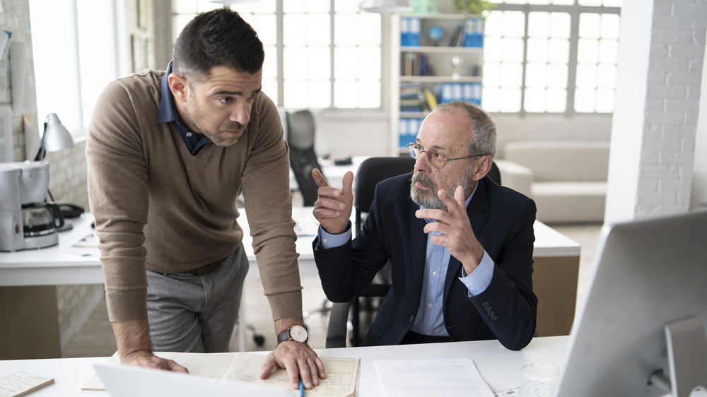 boss talking over employee's shoulder