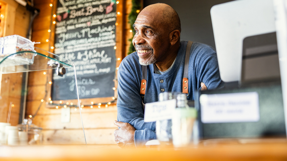 senior male cafe owner at front counter