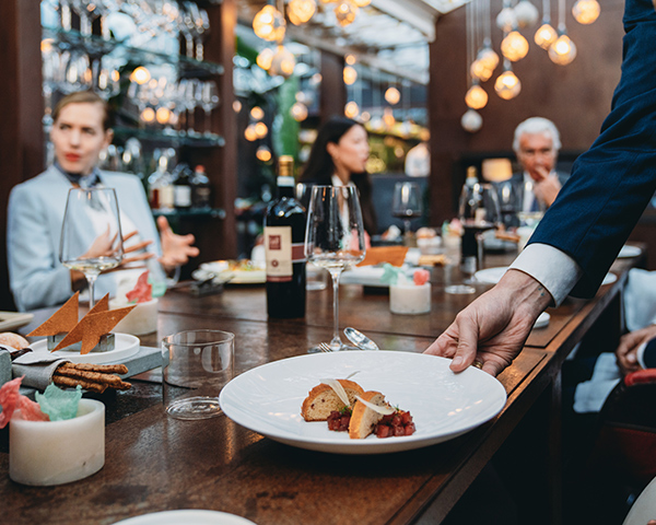 waiter presenting meal to group of people in fine restaurant