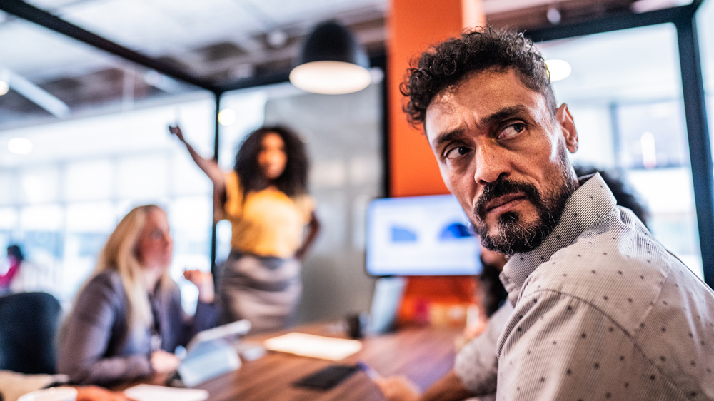 mature man looking disgusted in office meeting