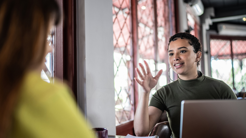 two women sitting at table having conversation