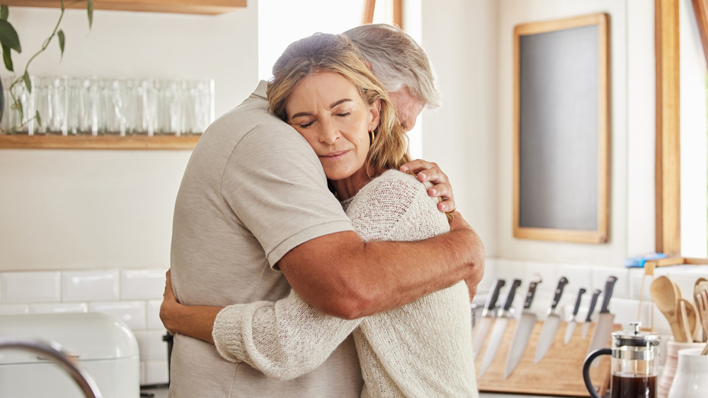 middle-aged husband and wife hugging in the kitchen