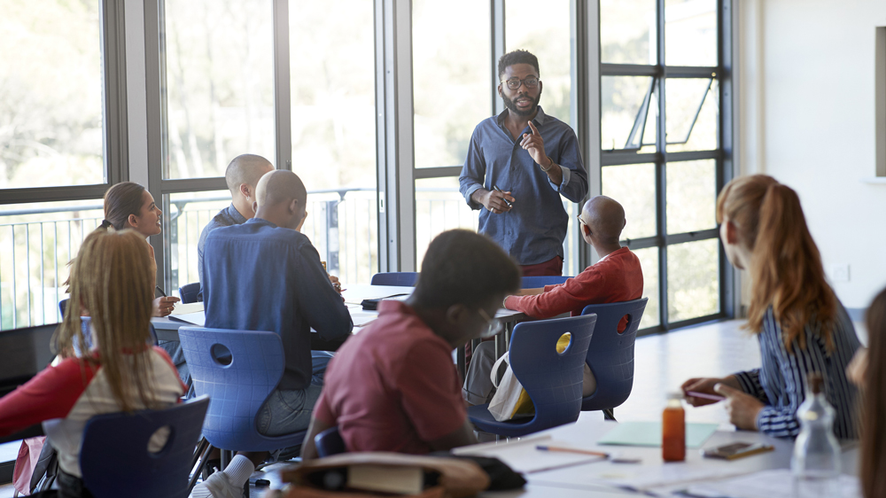 confident young male trainer teaching room of adults