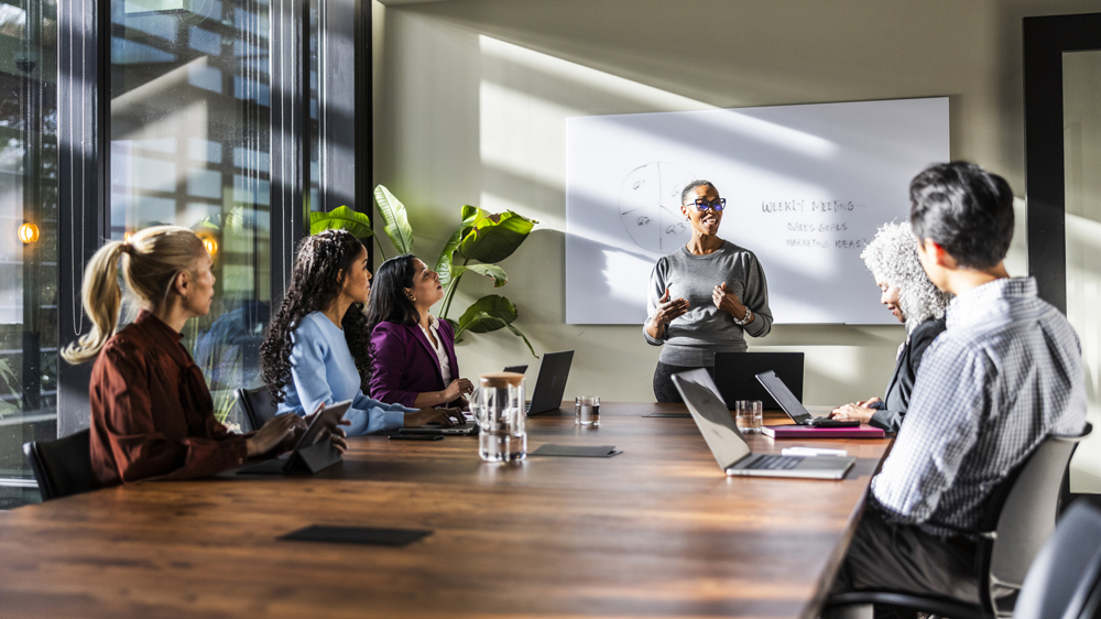 Female business owner speaking to office workers in modern conference room