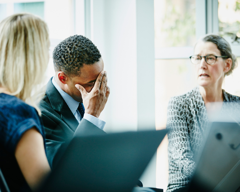 three people in business meeting looking frustrated